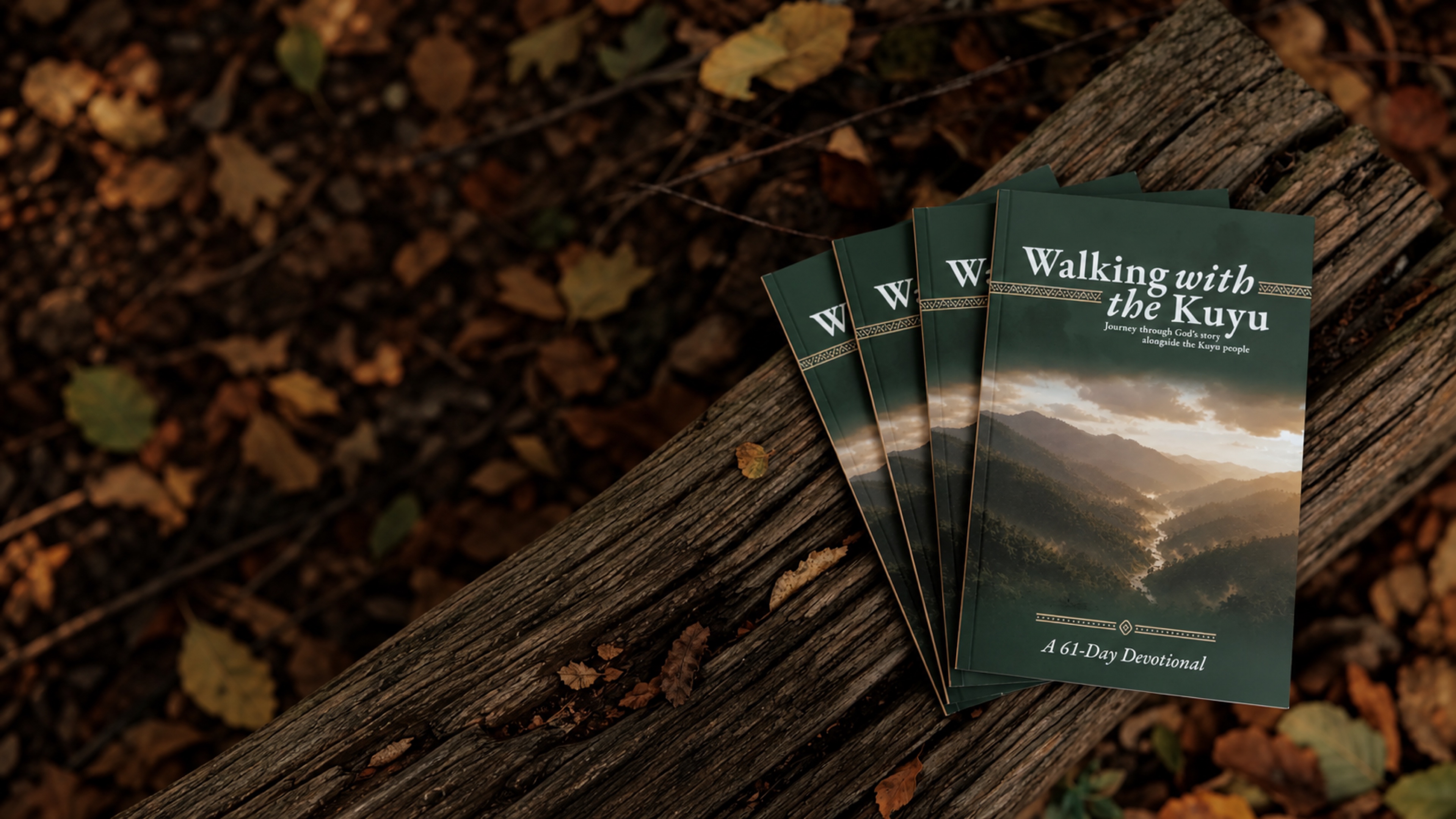 Copies of the Walking with the Kuyu devotional resting on a weathered fallen log.